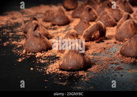 Schokoladentrüffel mit Kakaopulver auf schwarzem Hintergrund Stockfoto