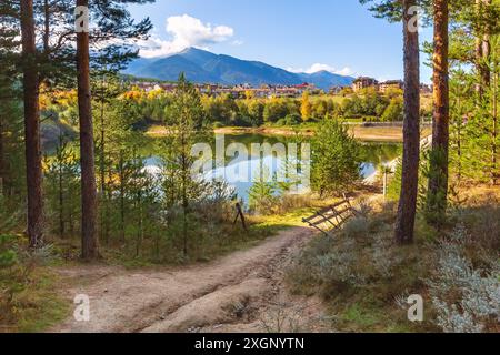 Bansko, Bulgarien Herbst Panorama Hintergrund der Pirin Berggipfel, See Damm Wasser, bunte grüne, rote und gelbe Bäume Reflexion Stockfoto