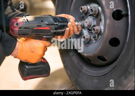 Kfz-Mechaniker Arbeiter tun Reifen oder Rad Austausch mit Elektroschlüssel in der Garage der Reparatur-Service-Station. Hochwertige Fotos Stockfoto