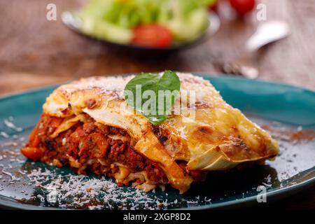 Ein Teil italienischer Lasagne auf einer blauen Platte Stockfoto