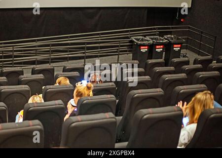 Die Zuschauer sitzen in der Kinohalle mit einer 3D-Brille mit Popcorn und einem Drink, bevor sie sich anschauen. Familienwochenende Stockfoto