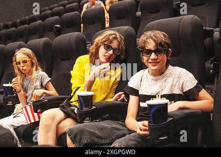 Kinder sitzen im Kinosaal mit Popcorn, bevor sie sich ansehen. Familienwochenende Stockfoto