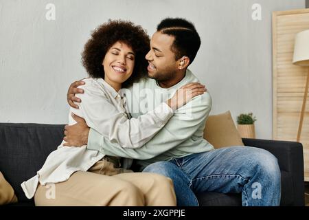 Ein afroamerikanisches Paar sitzt auf einer Couch und umschließt sich. Stockfoto