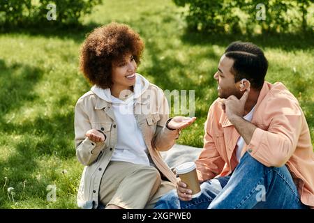 Ein junges afroamerikanisches Paar sitzt auf einer Decke in einem Park und kommuniziert mit Gebärdensprache. Stockfoto