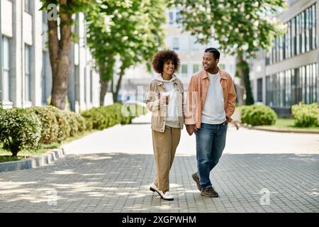 Ein junges afroamerikanisches Paar spaziert Hand in Hand auf einem gepflasterten Fußweg und genießt einen hellen, sonnigen Tag. Stockfoto