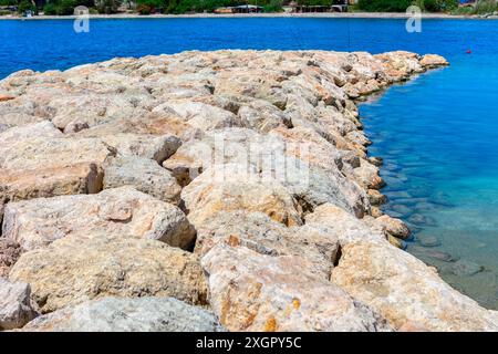 Felsiger Pier mit einem Wasserkörper im Hintergrund. Die Felsen sind groß und zerklüftet und führen zum Meer, was eine zerklüftete und natürliche Landschaft schafft Stockfoto