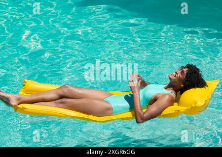 Die junge Frau genießt die Sonne auf einem Schwimmbecken mit Kopierraum. Sie entspannt sich in einem Swimmingpool, was Freizeit und Sommerstimmung bedeutet. Stockfoto