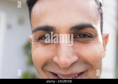Nahaufnahme eines lächelnden Mannes aus dem Nahen Osten draußen. Sein fröhlicher Ausdruck erhellt den sonnigen Tag. Stockfoto