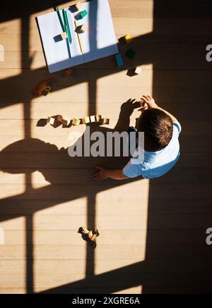 Draufsicht, Kinder und Blöcke zum Lernen zu Hause, Bildung und Spielzeug zum Spielen im Wohnzimmer. Oben, Junge und Kleinkind für kreative Aktivitäten Stockfoto