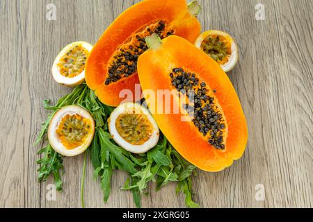 Papaya-Frucht, Passionsfrucht und Rucola auf hellem hölzernem Hintergrund. Scheiben süßer Papaya und Maracuja auf hölzernem Hintergrund, halbe Papayas, Kopie Stockfoto