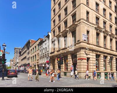 Altes Montreal, die Menschenmenge spaziert auf einem Kopfsteinpflaster zwischen zwei Gebäuden Stockfoto