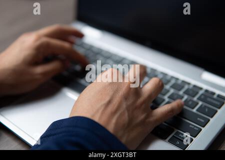 Ein Nahbild der Hände einer Person, die auf einer Laptop-Tastatur tippen. Produktivität, Arbeitsaufwand und Arbeitskonzept. Stockfoto