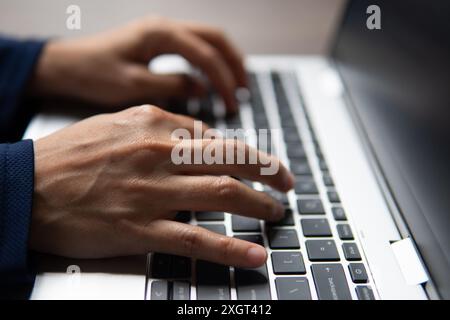 Ein Nahbild der Hände einer Person, die auf einer Laptop-Tastatur tippen. Produktivität, Arbeitsaufwand und Arbeitskonzept. Stockfoto