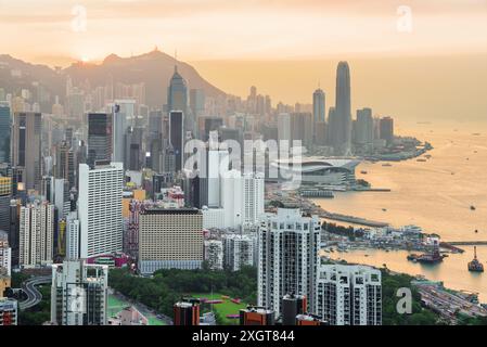 Wunderschöne Aussicht auf Hong Kong Island und Victoria Harbour bei Sonnenuntergang. Wolkenkratzer in der Innenstadt sind auf dem orangefarbenen Hintergrund zu sehen. Malerische Stadtlandschaft. Stockfoto