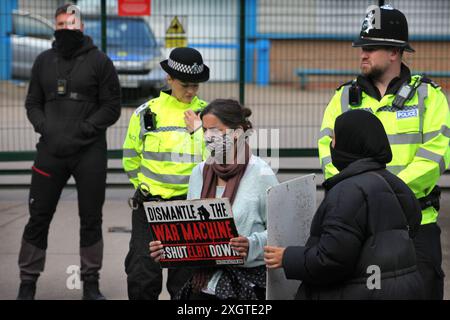 Leicester, Leicestershire, Großbritannien. Juli 2024. Polizisten und Elbit Security schützen den Eingang zur Fabrik, während Demonstranten während der Demonstration Schilder gegen Elbit Systems halten. Demonstranten versammeln sich vor den Toren der Fabrik von Elbit System in Leicester, um zu protestieren, während Arbeiter bei der israelischen Rüstungsfirma arbeiten. Die Demonstranten protestieren gegen die Waffen, die in dieser Fabrik hergestellt wurden, die ihrer Meinung nach später zur Unterdrückung der Palästinenser in Gaza und anderswo eingesetzt werden. 85 % der israelischen Drohnenflotte werden von Elbit Systems beliefert, und die Demonstranten wollen ihre sieben verbleibenden Geschäfte Stockfoto