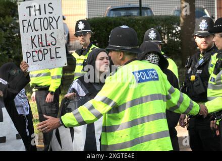 Leicester, Leicestershire, Großbritannien. Juli 2024. Ein Demonstrant hält ein Schild mit der Aufschrift „˜diese Fabrik tötet Menschen“ hoch, während die Polizei sie daran hindert, die Straße am Eingang der Fabrik während der Demonstration zu blockieren. Demonstranten versammeln sich vor den Toren der Fabrik von Elbit System in Leicester, um zu protestieren, während Arbeiter bei der israelischen Rüstungsfirma arbeiten. Die Demonstranten protestieren gegen die Waffen, die in dieser Fabrik hergestellt wurden, die ihrer Meinung nach später zur Unterdrückung der Palästinenser in Gaza und anderswo eingesetzt werden. 85 % der israelischen Drohnenflotte werden von Elbit Systems versorgt und die Demonstranten wollen ihre sieben Res Stockfoto