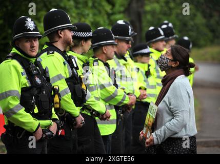 Leicester, Leicestershire, Großbritannien. Juli 2024. Polizeibeamte bilden am Eingang der Fabrik eine Absperrung, während Demonstranten während der Demonstration Schilder gegen Elbit Systems halten. Demonstranten versammeln sich vor den Toren der Fabrik von Elbit System in Leicester, um zu protestieren, während Arbeiter bei der israelischen Rüstungsfirma arbeiten. Die Demonstranten protestieren gegen die Waffen, die in dieser Fabrik hergestellt wurden, die ihrer Meinung nach später zur Unterdrückung der Palästinenser in Gaza und anderswo eingesetzt werden. 85 % der israelischen Drohnenflotte werden von Elbit Systems beliefert, und die Demonstranten wollen, dass ihre sieben verbleibenden Unternehmen geschlossen werden Stockfoto