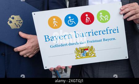 10. Juli 2024, Bayern, Donauwörth: Der Freistaat Bayern verewigt seine Unterstützung für den barrierefreien Bahnhof mit einem Schild, links ein Ordner mit dem Bundesadler. Foto: Stefan Puchner/dpa Stockfoto