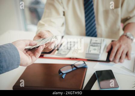 Ein Mann, der Hundert Dollar-Scheine anbietet. Hand eines Geschäftsmannes, der seinem Partner Geld gibt. Hand erhält Geld vom Geschäftsmann. Bestechung, Bestechung, Stockfoto