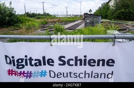 10. Juli 2024, Bayern, Donauwörth: Hinter einer Ankündigung für das Projekt Digital Rail wachsen Gräser und Kräuter auf einer Drehscheibe im Bahnhof. Die Deutsche Bahn hat auch das erste digitale Stellwerk Deutschlands auf einer Hochgeschwindigkeitsstrecke in Betrieb genommen. Foto: Stefan Puchner/dpa Stockfoto