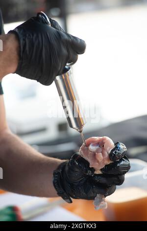 Hähnchenschenkel, die Marinade mit einer Spritze injizieren Stockfoto