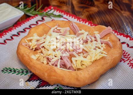 Langos mit Käse und Speck, ein typisch ungarisches Essen. Frittiertes Fladenbrot in Öl. Stockfoto