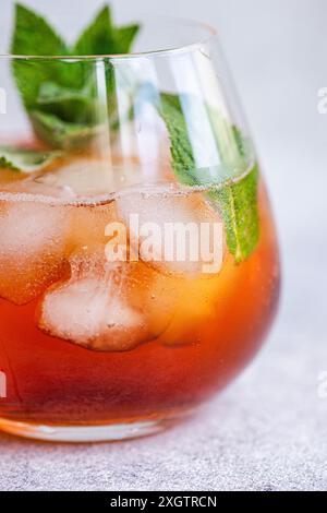 Nahaufnahme eines gekühlten Cola-Cocktails, wunderschön garniert mit frischen Minzblättern in einem klaren Glas. Eiswürfel und ein dezentes Fizz verstärken die ap des Getränks Stockfoto