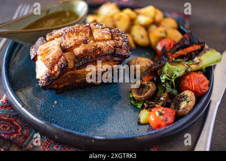 Knusprige gebackene Schweinerippchen, großzügig mit einer Honigsauce bespritzt, begleitet von einem Salat mit bunten gegrilltem Gemüse auf einer Keramikplatte Stockfoto
