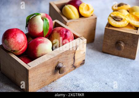 Reife Nektarinen und Pfirsiche, die in rustikalen Holzkisten ausgestellt werden, fangen das Wesen des Sommers mit ihren lebendigen Farben und dem saftigen Aussehen ein. Das Holz Stockfoto