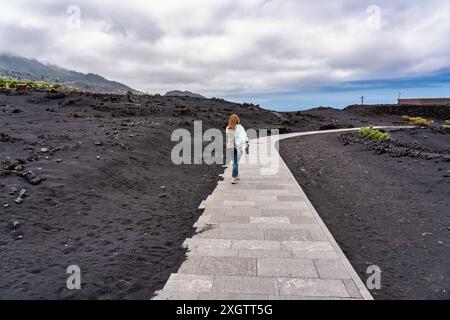 Touristen-Frau, die auf einem Fußweg spaziert, um die vulkanische Mondlandschaft auf der Insel La Palma auf den Kanarischen Inseln zu betrachten Stockfoto