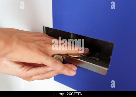 Frauenhände sammeln Münzen an einem Geldwechselautomaten Stockfoto