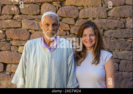 Ein marokkanischer Ältester in traditioneller Kleidung und eine Frau mittleren Alters teilen einen Moment der Freude vor einer Steinmauer in Marokko, Nordafrika Stockfoto