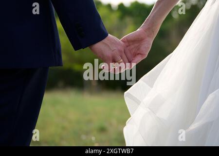Ein Nahaufnahme-Bild, das eine Braut und einen Bräutigam bei ihrer Hochzeit im Freien an Händen hält und damit Liebe und Engagement symbolisiert Stockfoto