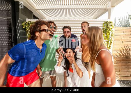 Verschiedene Freunde genießen ein fröhliches Treffen an einem sonnigen Tag, lachen und zeigen, um sommerliches Glück zu zeigen. Stockfoto