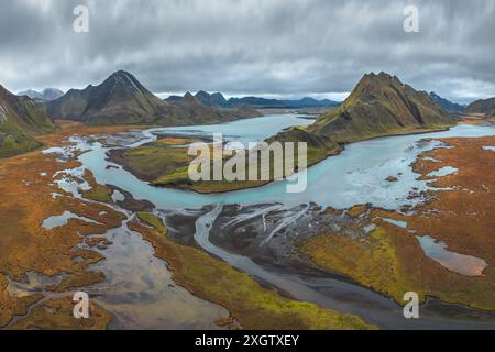 Ein atemberaubendes Panoramabild, das die raue Schönheit des isländischen Hochlands mit moosigen grünen Gipfeln und gewundenen Flüssen in der Mitte feststellt Stockfoto