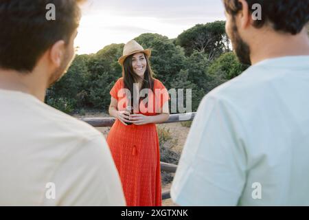 Anonyme Freunde treffen sich im Freien und genießen einen friedlichen Sonnenuntergang bei einem Bier. Das Bild erfasst nicht erkennbare Personen in einer offenen, entspannten Weise Stockfoto