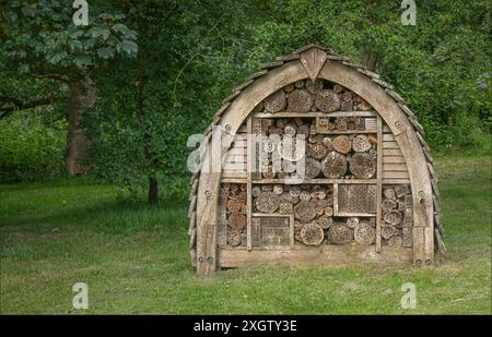 Großes bogenförmiges Käferhaus im Garten eines Herrenhauses an einem Rande in der Nähe einiger Bäume Stockfoto