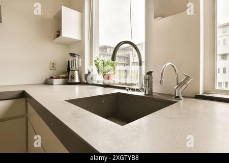 Eine schicke, moderne Küche in Henkenshage, Amsterdam, mit einer eleganten Arbeitsplatte und einem Waschbecken aus Edelstahl. Das große Fenster bietet einen Blick auf die urbane Umgebung Stockfoto
