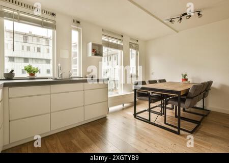 Eine geräumige, moderne Küche mit weißen Schränken und einem hölzernen Essbereich in einem hellen Amsterdamer Apartment in Henkenshage Stockfoto