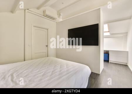 Ein geräumiges und sauberes Schlafzimmer in der Hilversumstraat in Amsterdam, mit großem Bett, an der Wand montiertem Fernseher, weißen Schränken und minimalistischem Dekor S Stockfoto