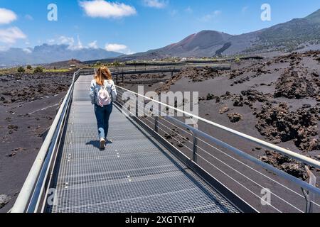 Touristenfrau, die auf einem Pfad zwischen Felsen und Vulkanasche auf der Insel La Palma, Kanarischen Inseln, spaziert. Stockfoto