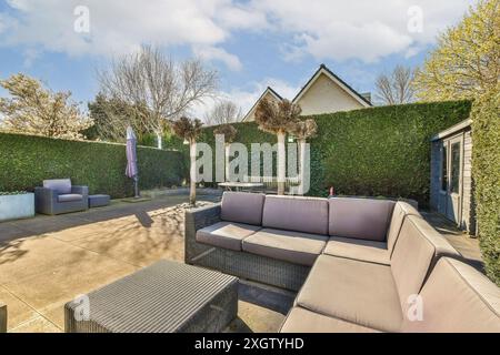 Eine einladende Terrasse im Freien in Jan Weilandlaan in den Niederlanden, mit modernen Loungemöbeln, gepflegten Hecken und geschmackvoll Stockfoto