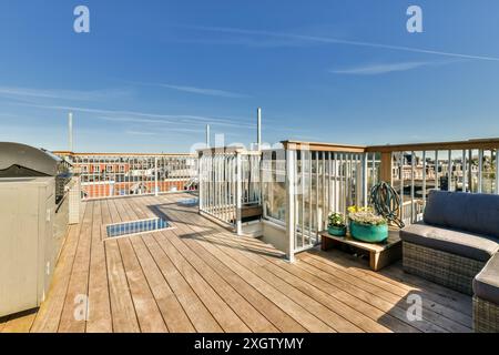 Moderne Dachterrasse mit Holzfußboden, bequemen Sitzgelegenheiten, verschiedenen Topfpflanzen und Panoramablick auf die Skyline der Stadt unter einem Klo Stockfoto