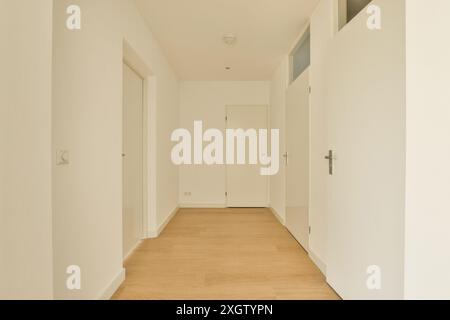 Ein eleganter und einfacher Flur in einem modernen Apartment in Amerbos 106, mit einfachen Wänden, Holzboden und mehreren Türen, die zu den Zimmern führen Stockfoto