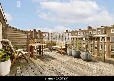 Eine charmante, sonnendurchflutete Dachterrasse mit stilvollen Holzmöbeln, Topfpflanzen und Blick auf die umliegenden Wohngebäude. Stockfoto