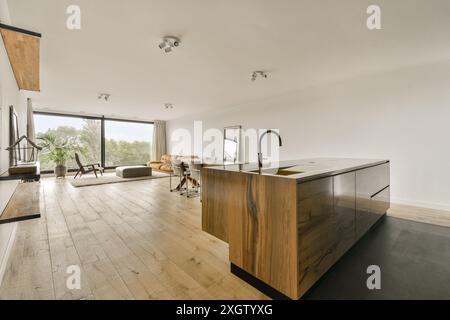 Geräumige, moderne Küche mit einer großen Insel, hohen Decken und einem offenen Grundriss, der sich bis zu einem komfortablen Wohnbereich mit weitläufigem Wind erstreckt Stockfoto