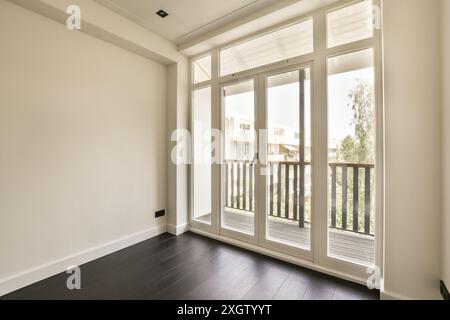 Ein luftiges und helles, modernes Zimmer mit großen deckenhohen Fenstern, die zu einem Balkon mit Panoramablick führen, ideal für Innenarchitekturen. Stockfoto