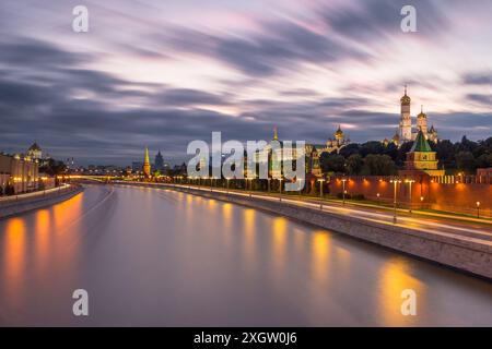 Moskauer Kreml und Moskwa Fluss bei Sonnenuntergang. Verkehrswege, sich bewegende Wolken und dramatischer Himmel. Blick von der Bolschoi-Moskworetski-Brücke. Stockfoto