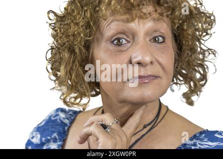 Das Bild zeigt eine 60-jährige Frau, die vor weißem Hintergrund steht. Stockfoto