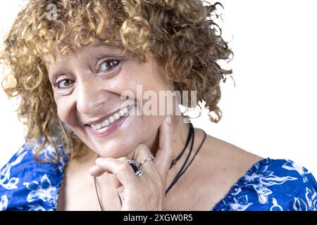 Das Bild zeigt eine 60-jährige Frau, die vor weißem Hintergrund steht. Stockfoto